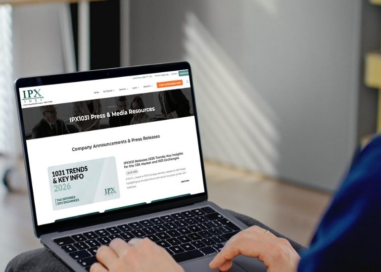 Person sitting with a laptop, viewing the IPX1031 Press & Media Resources webpage, which displays company announcements, press releases, and a featured section on “1031 Trends & Key Info 2026.”.